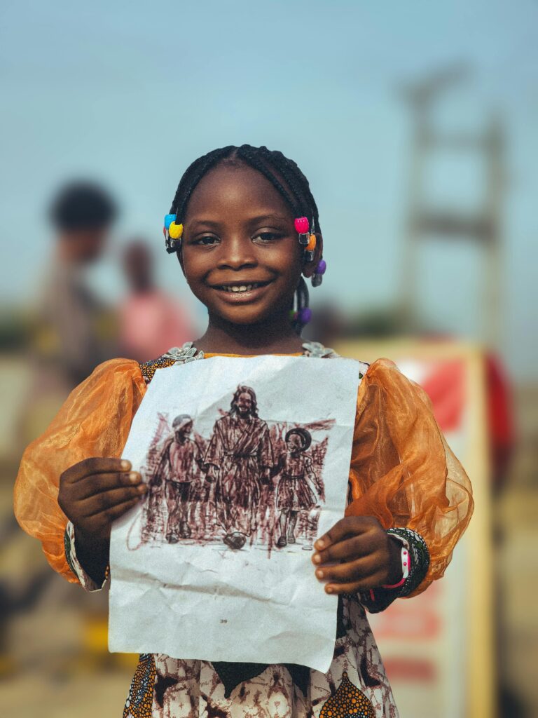 A cheerful young girl holding a detailed drawing, standing outdoors with a vivid smile.