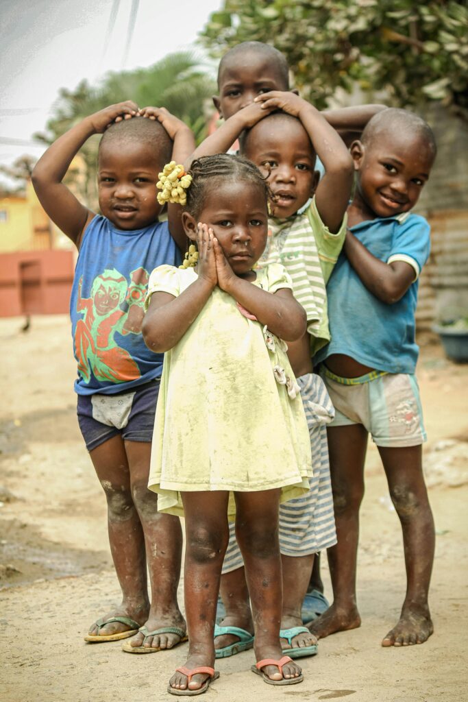 Five joyful children pose playfully in a sunny outdoor setting, capturing the essence of childhood.